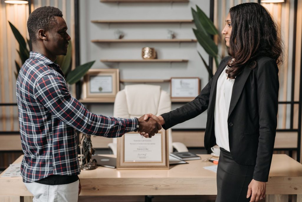 Two professionals shaking hands in an office, symbolizing a successful business agreement.